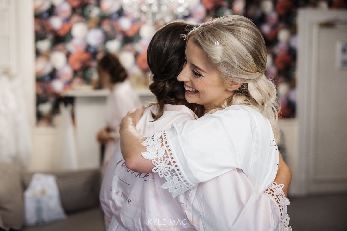 bride hugging bridesmiad bartle hall