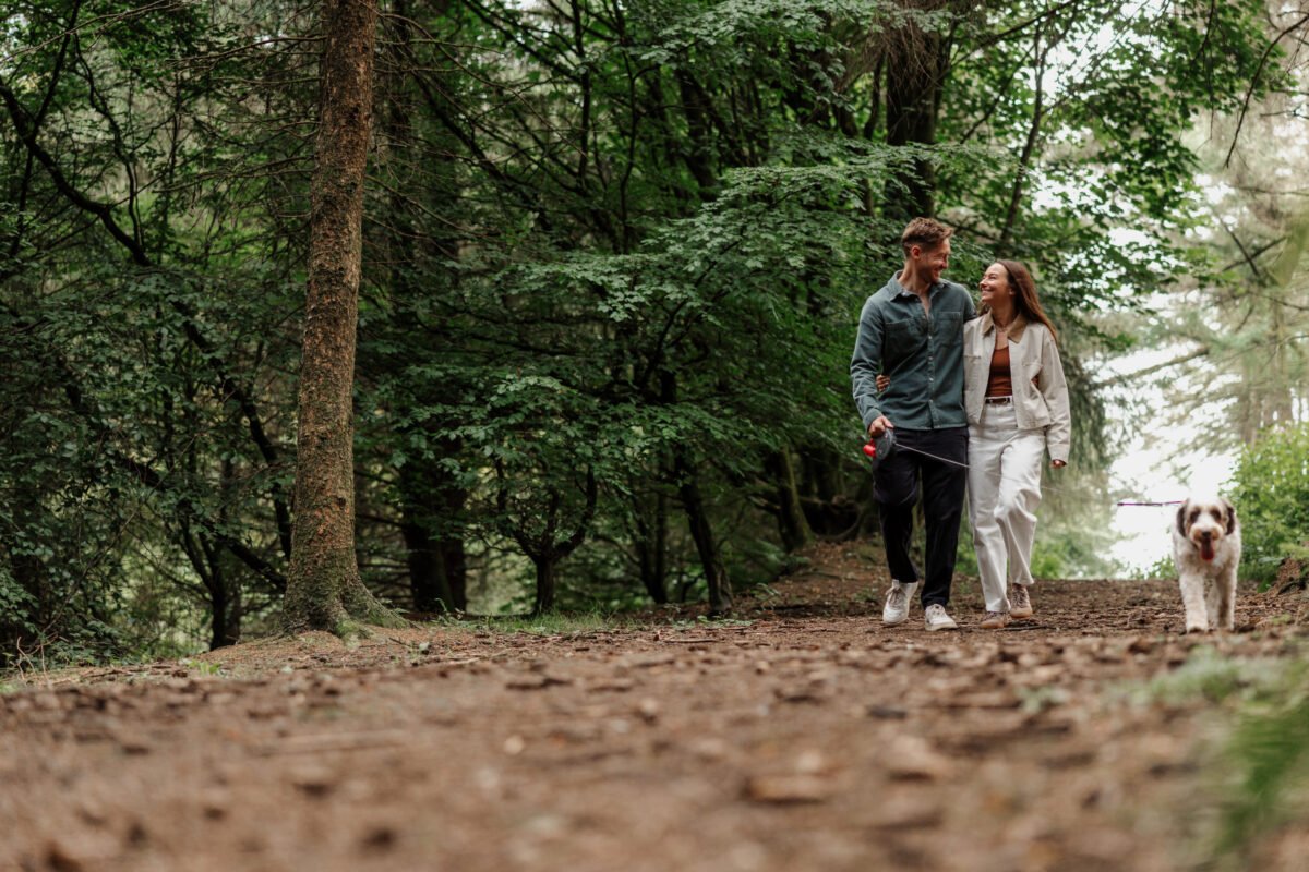 walking through the trees with pet dog engagment photoshoot
